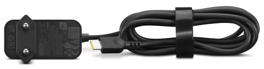 Czarny zasilacz Lenovo 65W USB-C na białym tle, przedstawiony w ułożeniu poziomym od boku. Po lewej stronie widoczna jest płaska wtyczka sieciowa z profilu wraz z certyfikatami, a obok leży starannie zwinięty i spięty rzepem czarny kabel. Wtyk USB-C z żółtym elementem jest wyeksponowany pośrodku kadru.