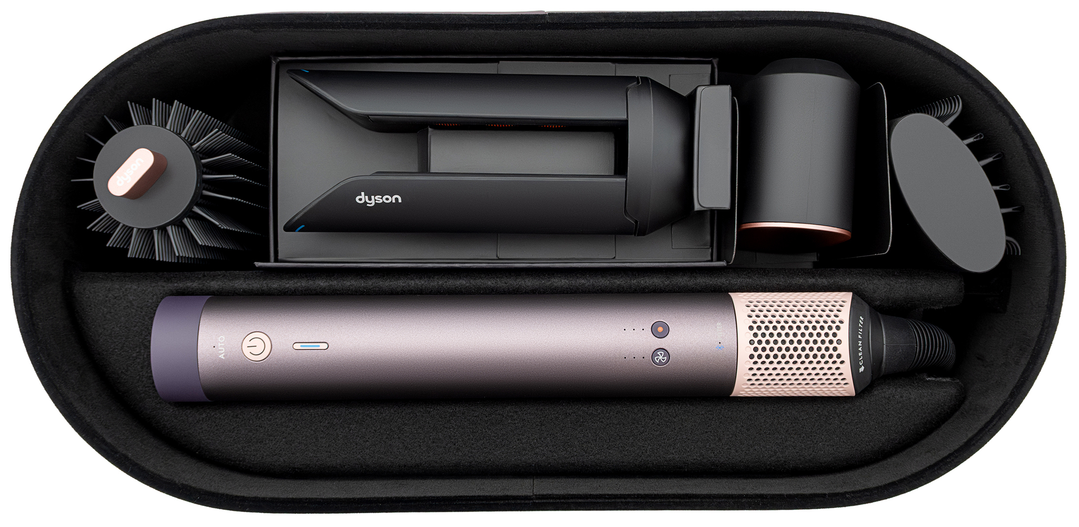 Zestaw Dyson Airwrap Multistyler w kolorze fioletowego jaspisu ułożony w czarnym, owalnym etui. Wewnątrz znajduje się główny moduł urządzenia oraz cztery wymienne końcówki stylizujące, które są dopasowane do dedykowanych przegródek w etui.