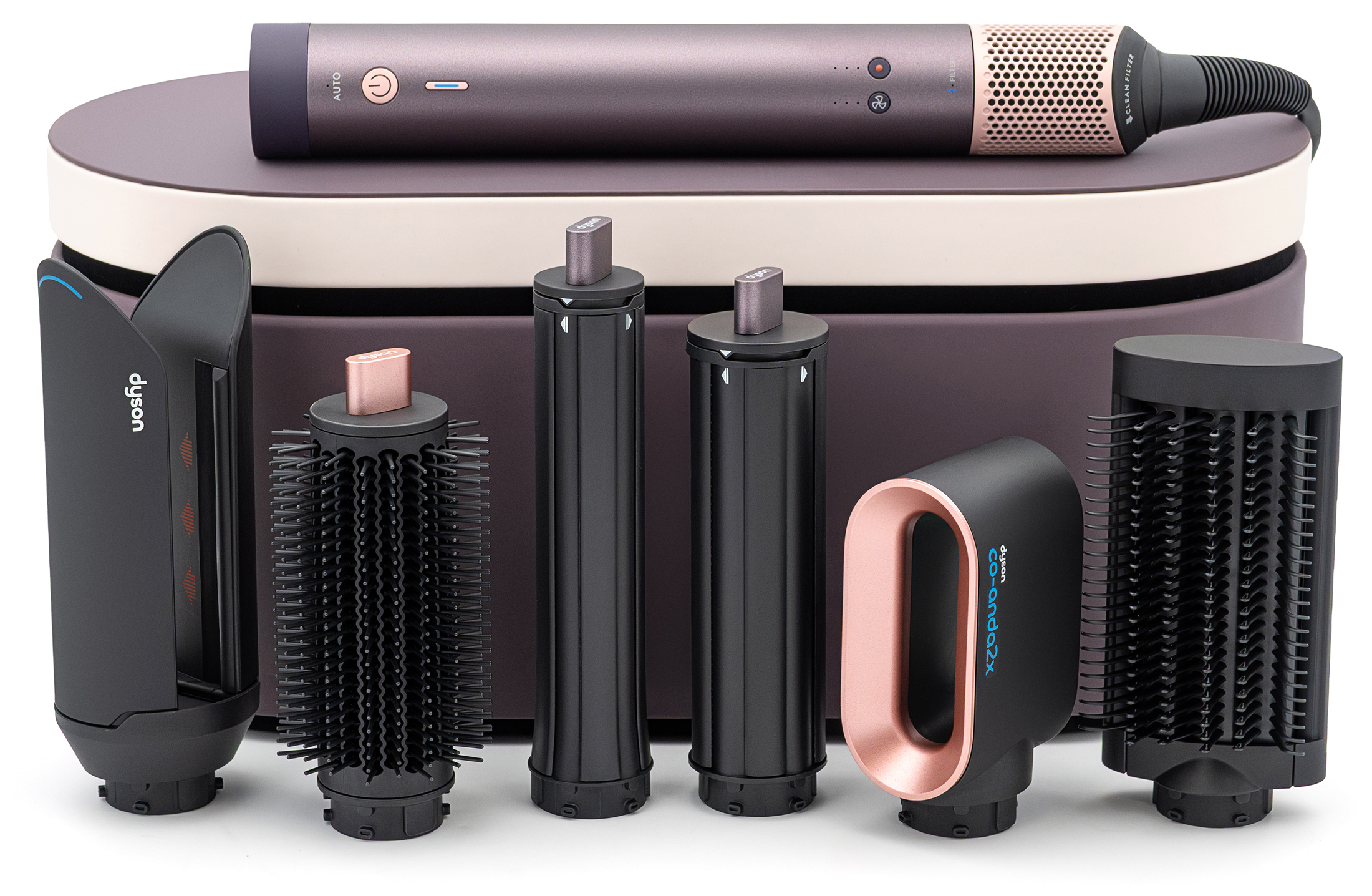Zestaw Dyson Airwrap Multistyler w kolorze fioletowego jaspisu. Główny moduł urządzenia spoczywa na etui, a obok niego ustawiono w rzędzie sześć wymiennych końcówek do stylizacji, w tym nasadkę Co-anda i szczotki.