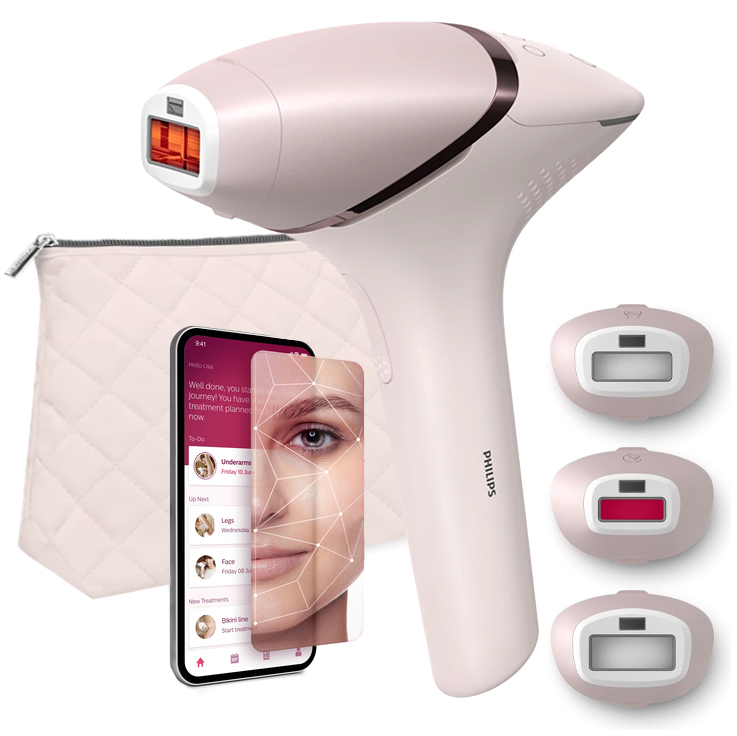 Różowy depilator IPL Philips Lumea 9900 z zestawem trzech wymiennych nasadek i pikowaną kosmetyczką na białym tle. Obok widoczny jest smartfon z aplikacją mobilną Philips Lumea IPL, która wspomaga planowanie zabiegów. Urządzenie ma elegancki, perłowy design z miedzianymi detalami.