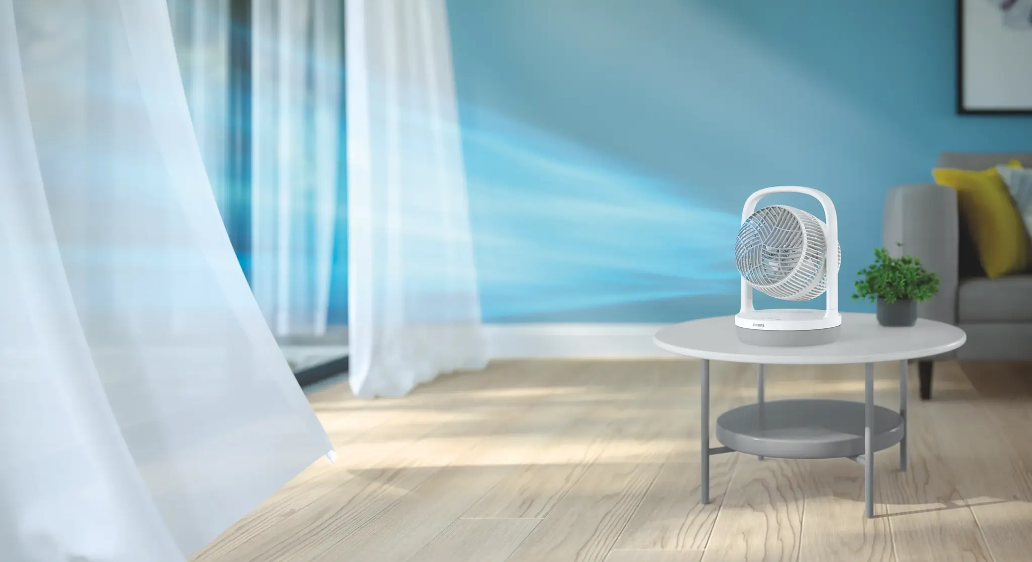 Biały wentylator biurkowy Philips Seria 2000 CX2050/00 emituje błękitny strumień powietrza, który porusza białą zasłoną w salonie. Urządzenie stoi na okrągłym stoliku obok zielonej rośliny w przytulnym wnętrzu.