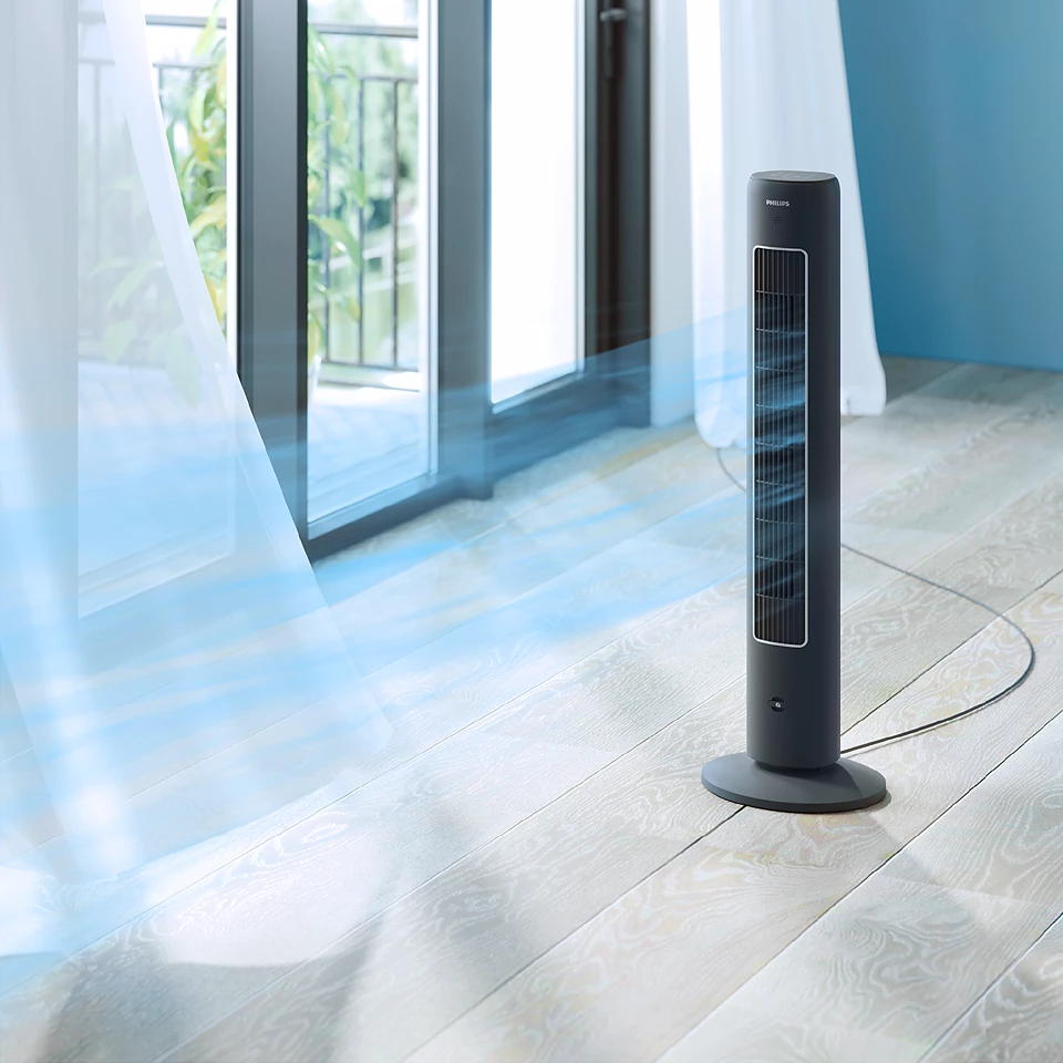 Czarny wentylator kolumnowy Philips CX5535/11 wydmuchuje niebieski strumień powietrza, stojąc w pokoju z otwartymi drzwiami balkonowymi i powiewającymi firankami.