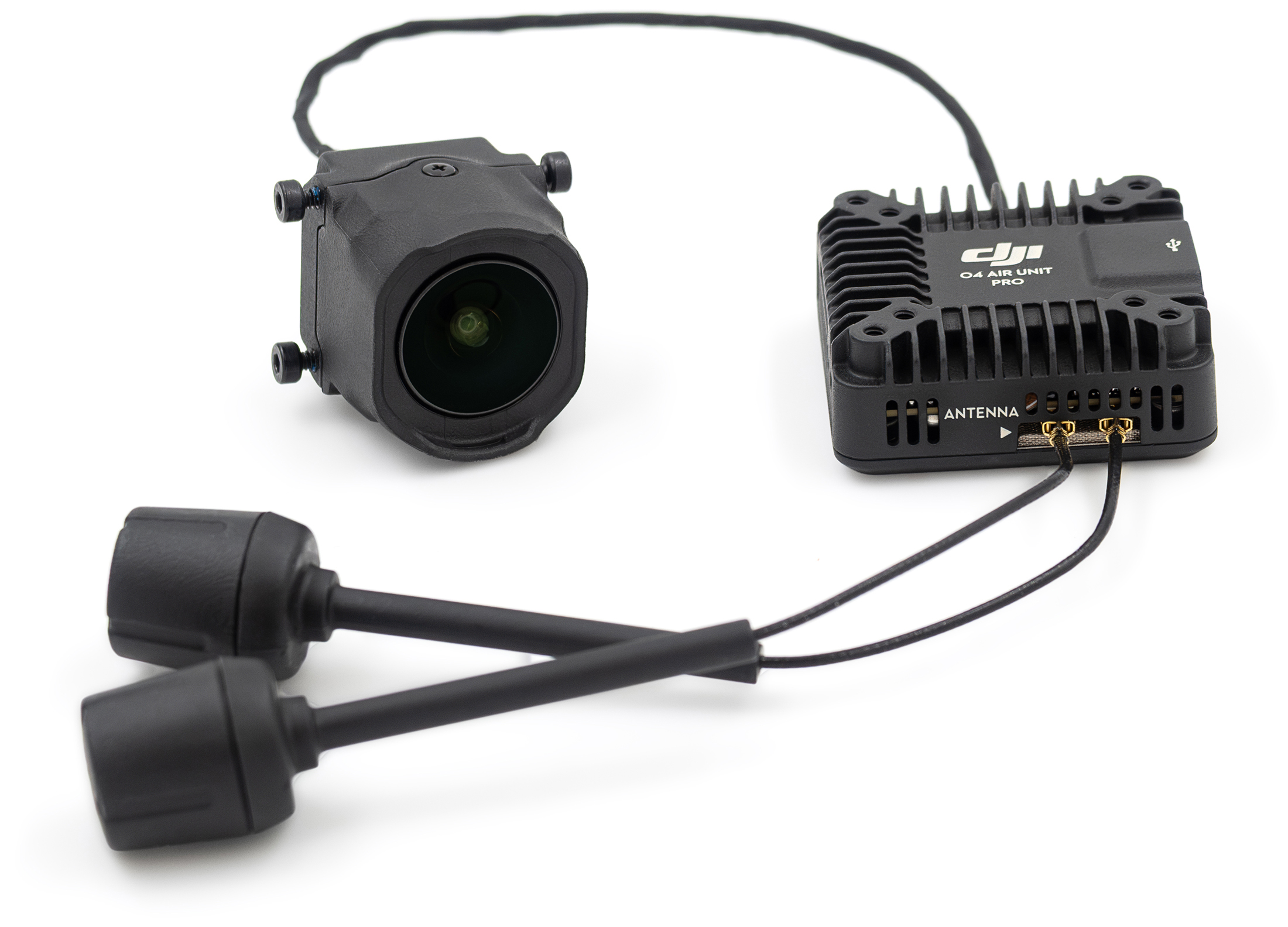 System transmisji DJI O4 Air Unit Pro przedstawiony bez opakowania na białym tle. Ujęcie ukazuje połączone czarnymi przewodami komponenty: żebrowany moduł główny z białym logo DJI, sześcienną miniaturową kamerę z dużym obiektywem oraz dwie podłużne anteny walcowe leżące w dolnej części kadru.