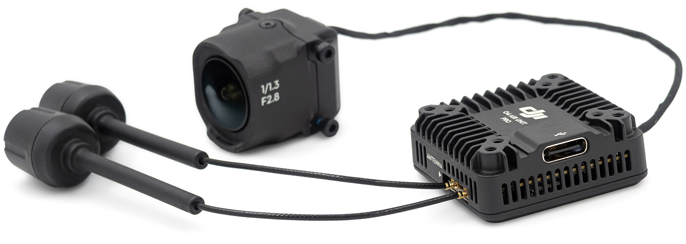 System transmisji DJI O4 Air Unit Pro pokazany od boku pod kątem na białym tle. Zdjęcie prezentuje połączone przewodem komponenty, wysuwając na pierwszy plan żebrowany moduł główny z logo DJI i portem USB-C oraz dwie czarne anteny walcowe. W tle po lewej stronie widoczna jest niewielka kamera z białym oznaczeniem obiektywu 1/1.3 F2.8.