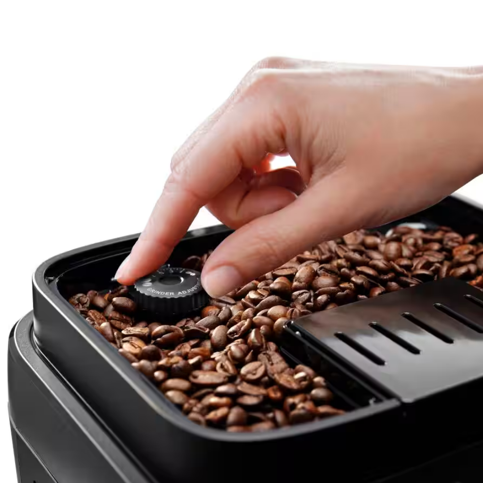 Zbliżenie na pojemnik ekspresu DeLonghi z ziarnami kawy, gdzie dłoń reguluje pokrętłem stopień mielenia.