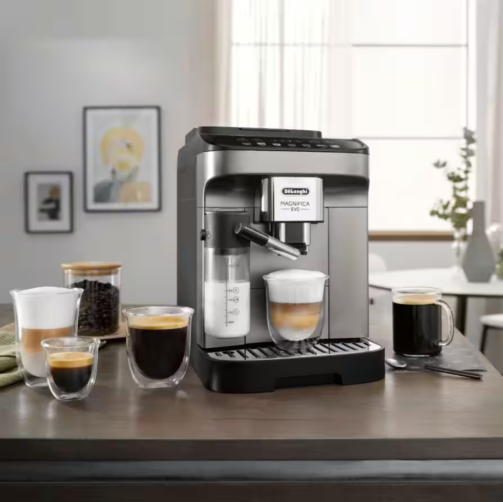 Ekspres DeLonghi Magnifica Evo ECAM290.81.TB na stole, przygotowujący kawę, obok stoją dwie gotowe kawy i słoik z ziarnami.