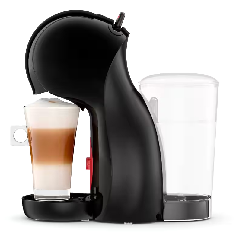 Czarny ekspres kapsułkowy DeLonghi Piccolo XS w widoku z boku. Zdjęcie ukazuje szklankę z kawą latte pod wylotem oraz duży, przezroczysty zbiornik na wodę z tyłu urządzenia. Kompaktowa konstrukcja z wyraźnymi czerwonymi akcentami przycisków i dźwigni.