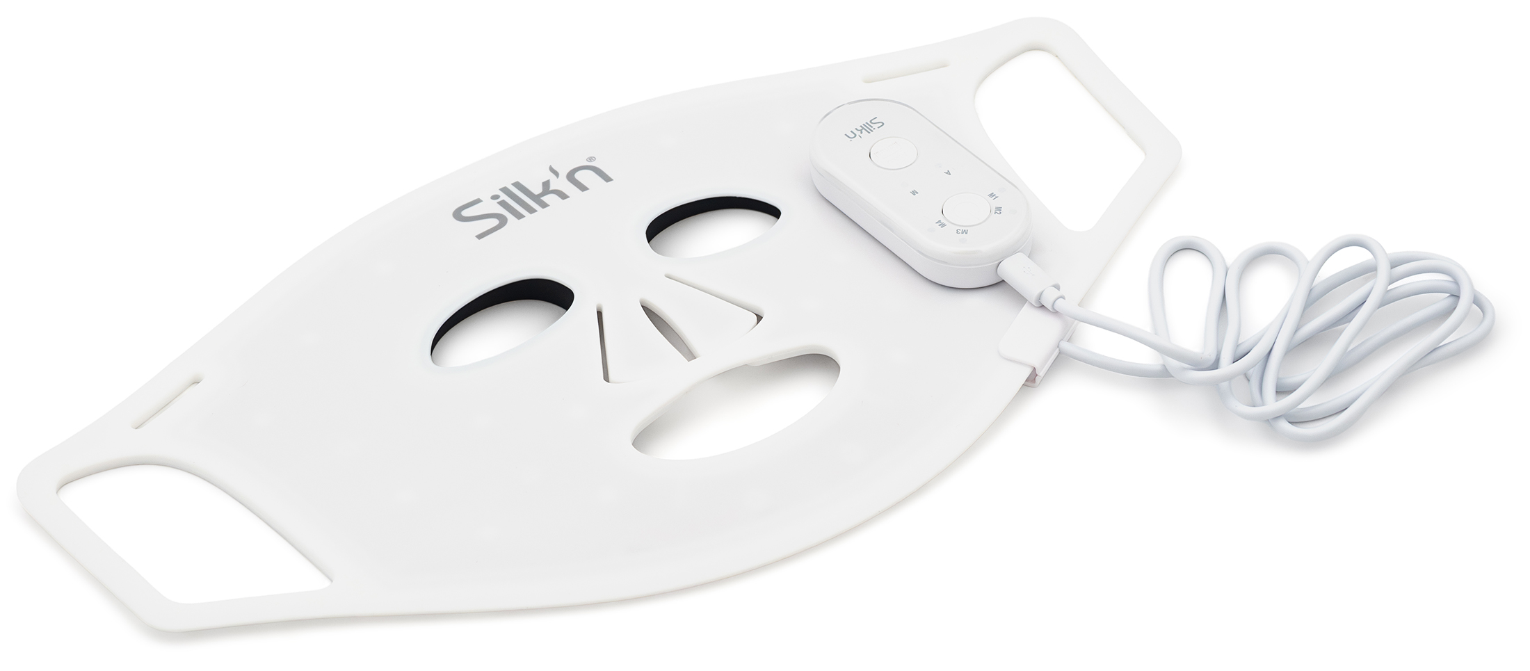 Wyłączona biała maska LED Silk'n Facial LED Mask 100 zaprezentowana pod kątem w pozycji leżącej na płasko na białym tle. Do bocznej części silikonowej konstrukcji z ergonomicznymi otworami podłączony jest biały, owalny pilot sterujący z widocznymi przyciskami i oznaczeniami trybów M1-M4. Obok kontrolera leży zwinięty biały przewód zasilający USB.