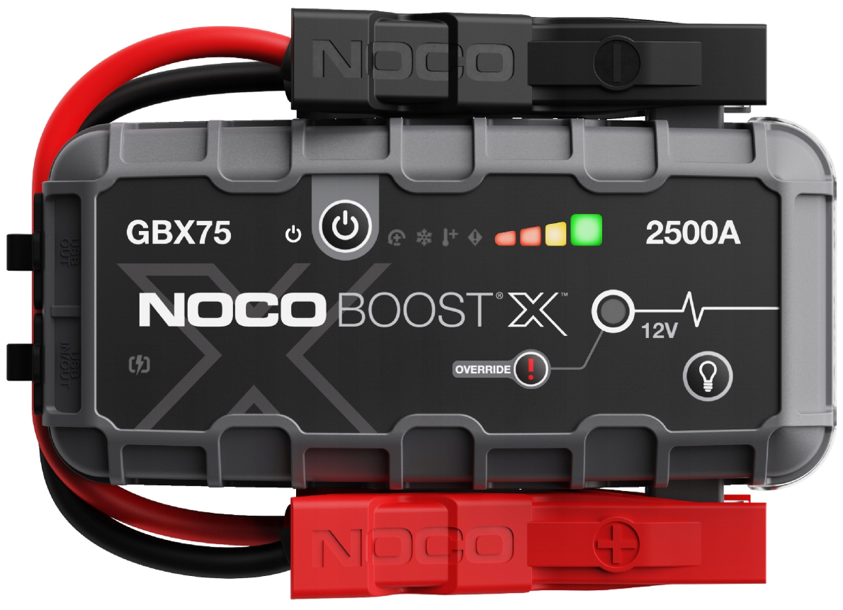 Urządzenie rozruchowe NOCO Boost X GBX75 z czerwonym i czarnym zaciskiem, widok od frontu na białym tle. Na panelu widoczne jest logo marki, wskaźnik naładowania LED, ikona latarki oraz przycisk trybu Override.
