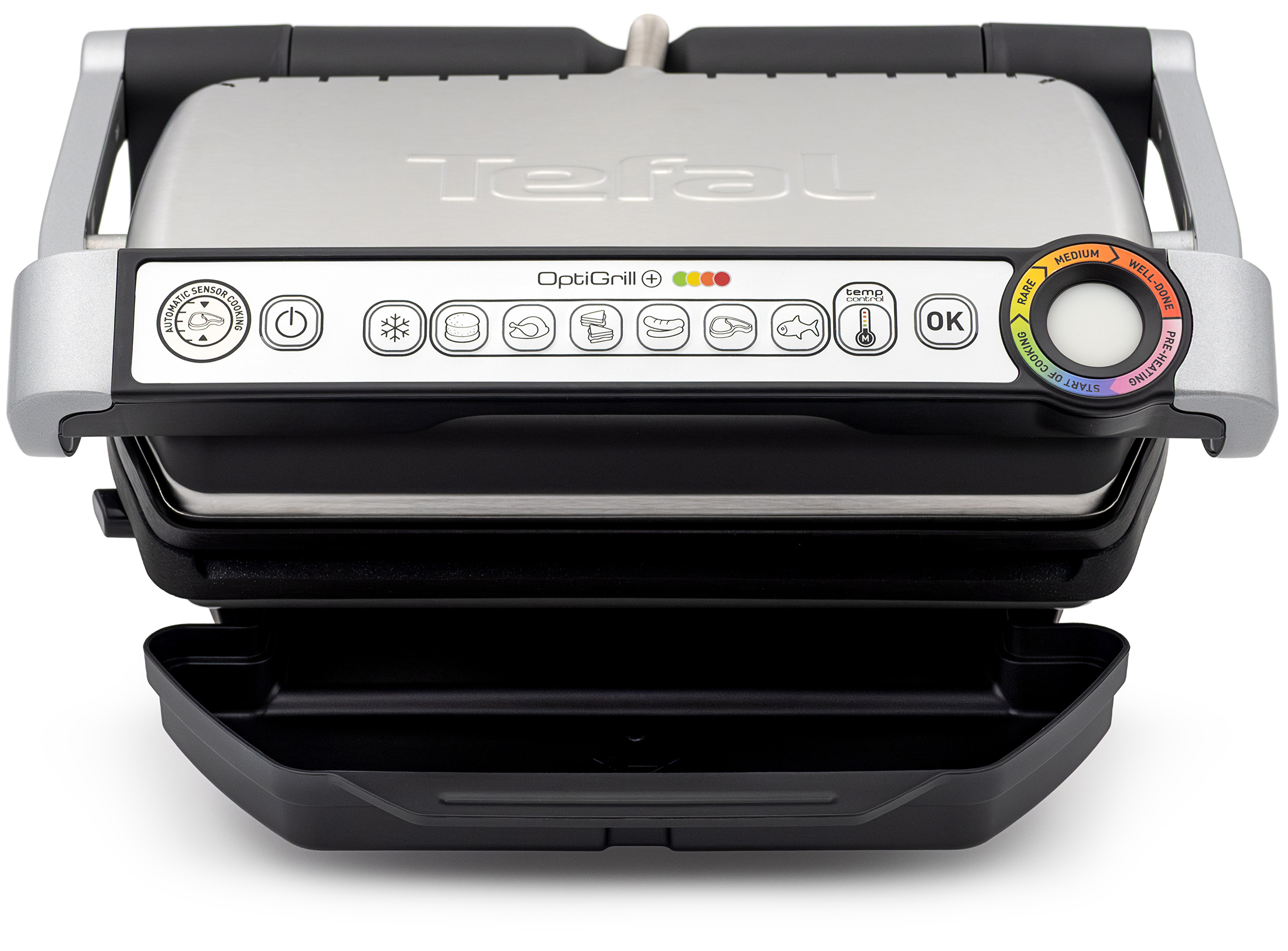 Grill elektryczny Tefal GC716D12 OptiGrill+ w ujęciu od przodu na białym tle. Urządzenie z metalową, srebrną pokrywą przedstawione jest w pozycji zamkniętej z wysuniętą dolną, czarną tacą ociekową. W rączce urządzenia wyraźnie wyeksponowano podłużny panel sterowania z ikonami programów automatycznych oraz charakterystycznym, okrągłym wskaźnikiem stopnia wysmażenia potraw.