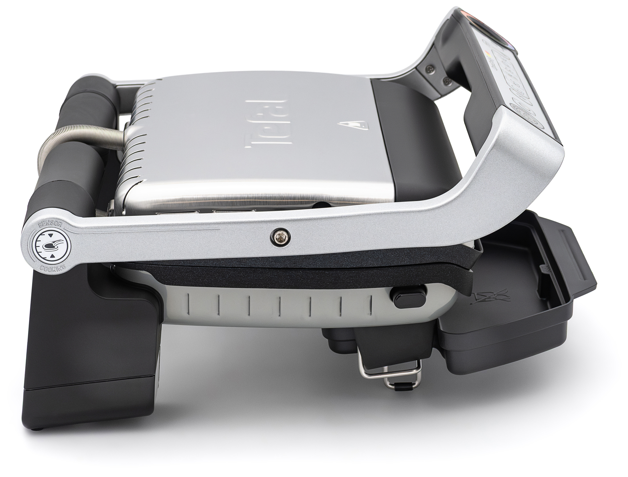 Zamknięty grill elektryczny Tefal GC716D12 OptiGrill+ w srebrno-czarnej obudowie, zaprezentowany z lewego boku na białym tle. Z tej perspektywy widoczne jest podłużne metalowe ramię rączki, wysunięta z przodu taca na tłuszcz oraz konstrukcja tylnego zawiasu z metalową osłoną kabla.