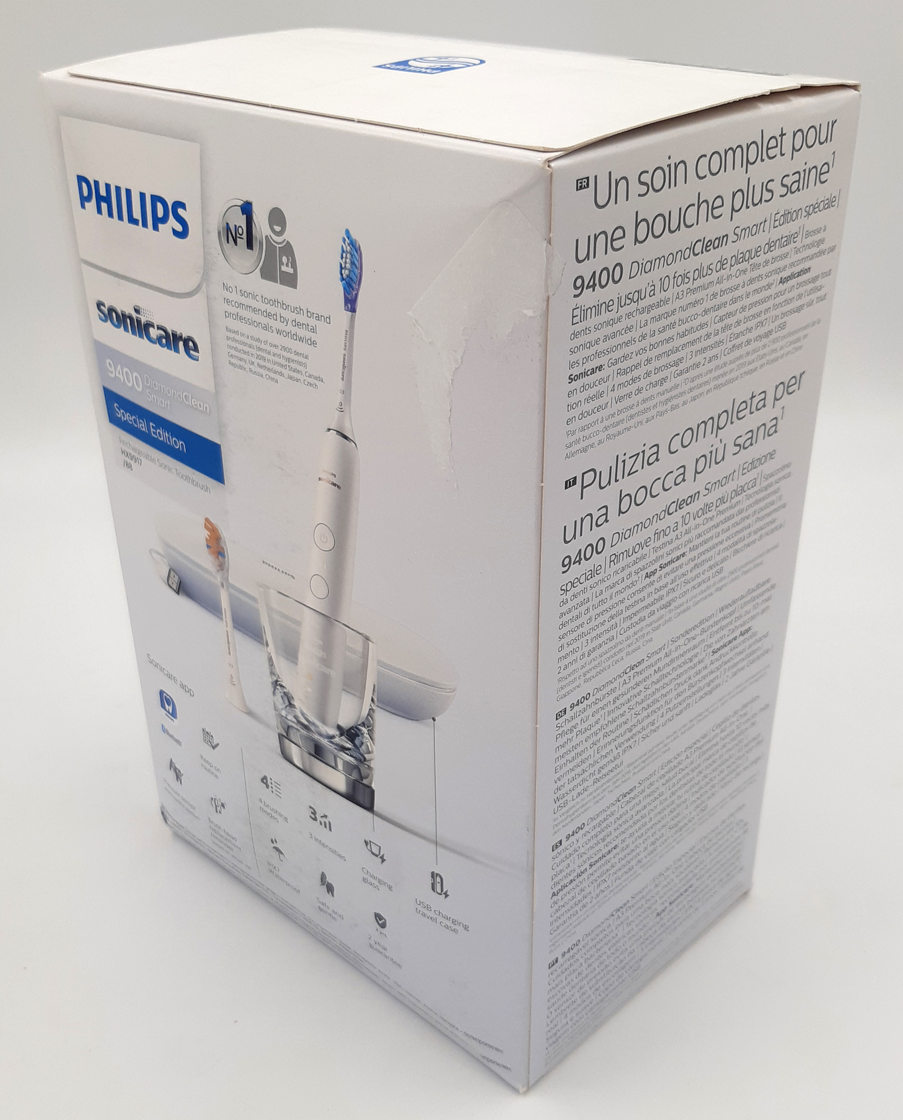 Białe pudełko szczoteczki Philips Sonicare DiamondClean Smart z widocznymi uszkodzeniami mechanicznymi. Karton ma wgniecenia na krawędziach oraz naderwany i zagięty prawy górny róg. Zdjęcie prezentuje stan opakowania zewnętrznego pod kątem.