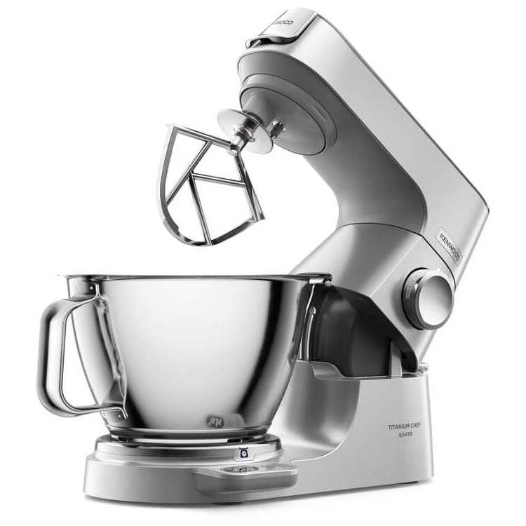 Robot planetarny Kenwood Titanium Chef Baker z podniesionym ramieniem i zamontowanym mieszadłem typu K. Widok z boku na białym tle pokazuje pustą, stalową misę oraz detale obudowy, w tym pokrętło sterowania i panel wagi.
