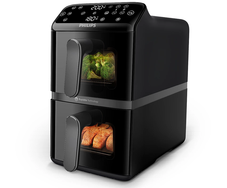 Frytkownica Philips Airfryer Dual Basket w kolorze czarnym. Urządzenie posiada dwie komory z okienkami podglądu, w których widać przyrządzane warzywa i rybę. Na górze znajduje się cyfrowy panel sterowania z wyświetlaczem temperatury i czasu dla obu stref gotowania.